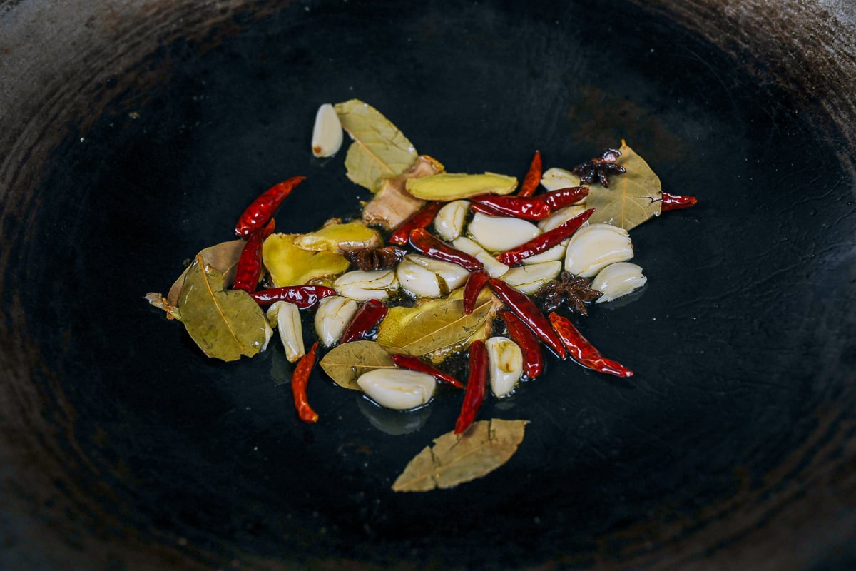 ginger, garlic, chilies, star anise, bay leaves in wok