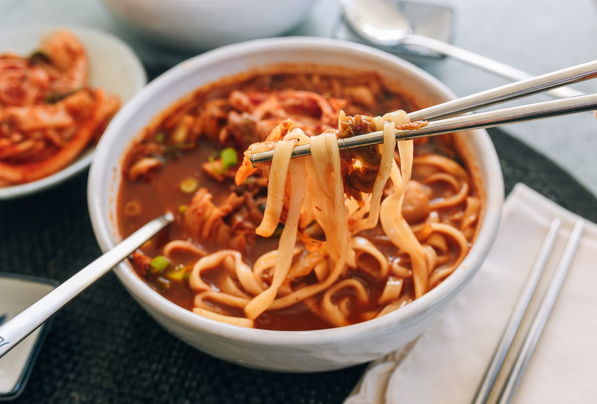 picking up noodles from bowl of kimchi soup