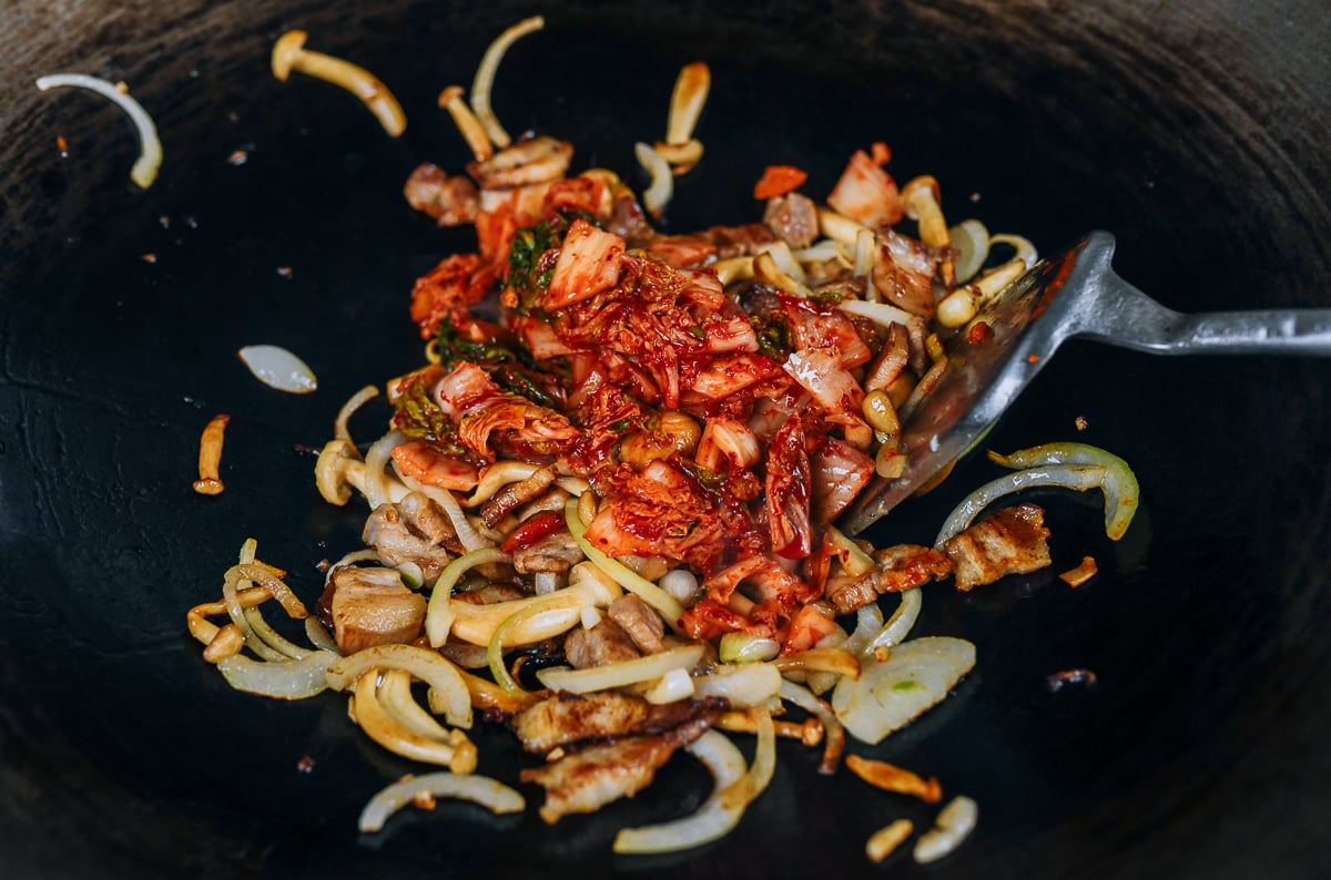 kimchi added to wok with pork and mushrooms