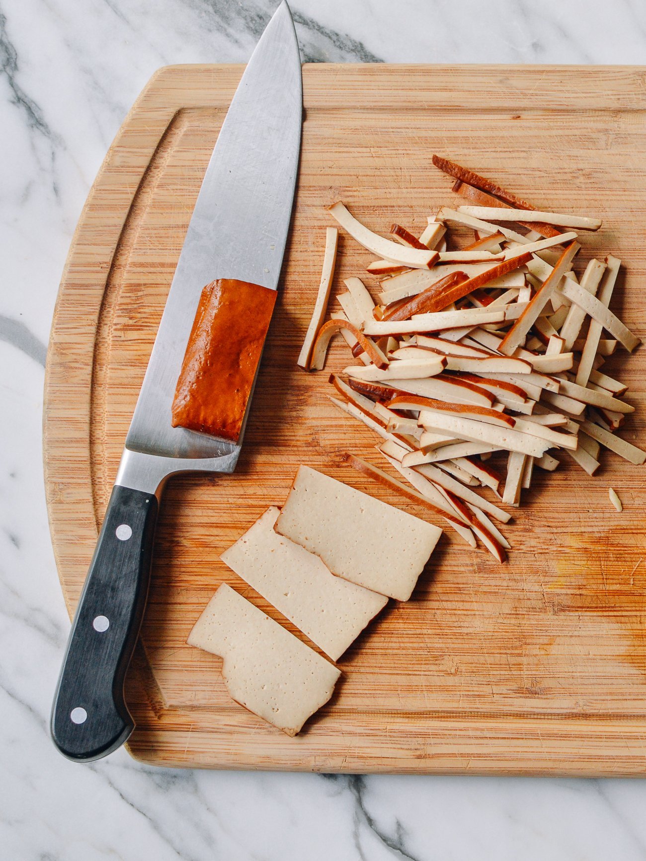 slicing pressed tofu or doufugan on cutting board